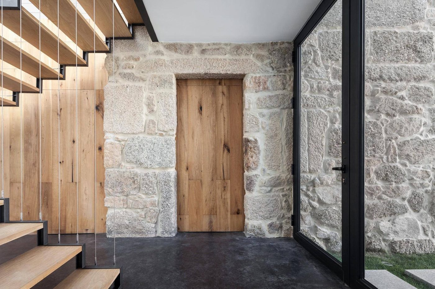 Entrée en pierre et escalier en bois d'un logement de charme créé dans une maison